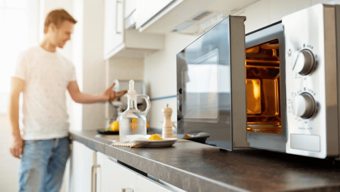 woman putting a bowl into a microwave to add steam so she can clean the microwave