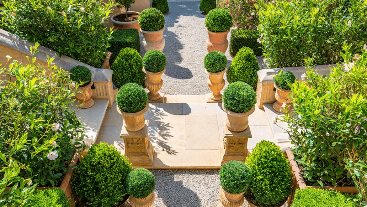 French garden with a brick arched way covered in ivy, and an antique wrought iron long dining table with vintage cane chairs underneath.