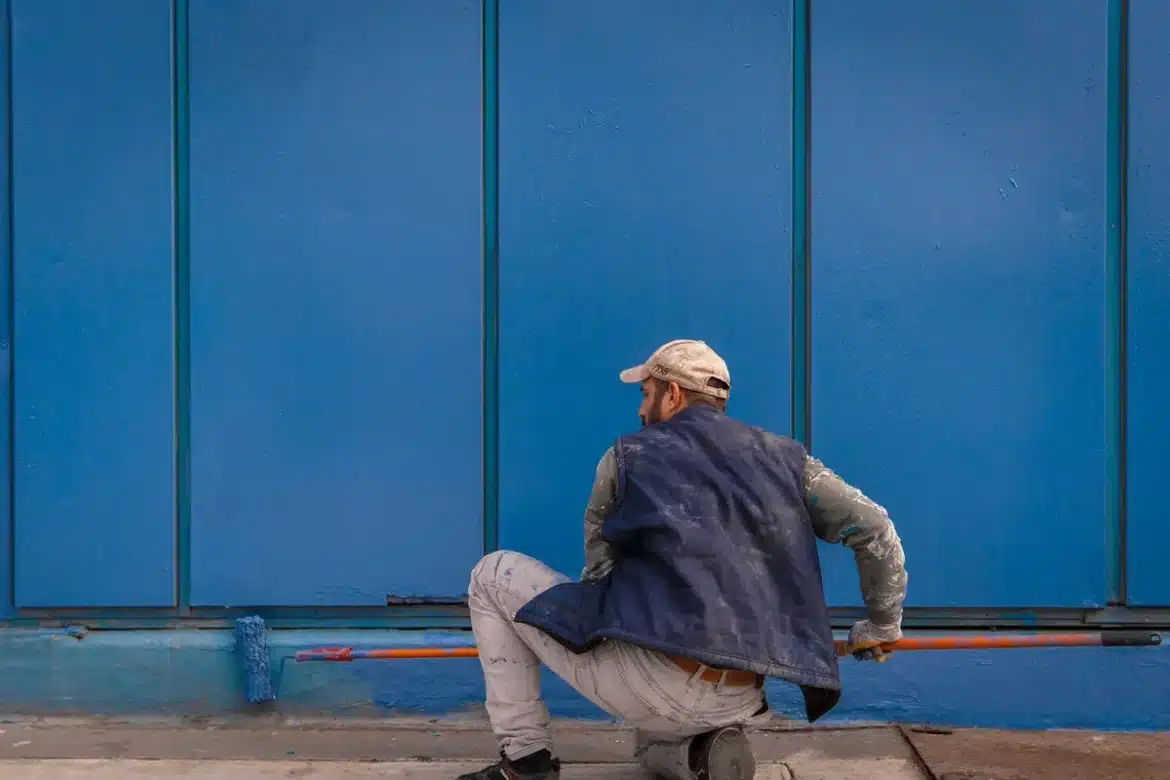 Personne peignant une terrasse en béton avec un rouleau et de la peinture