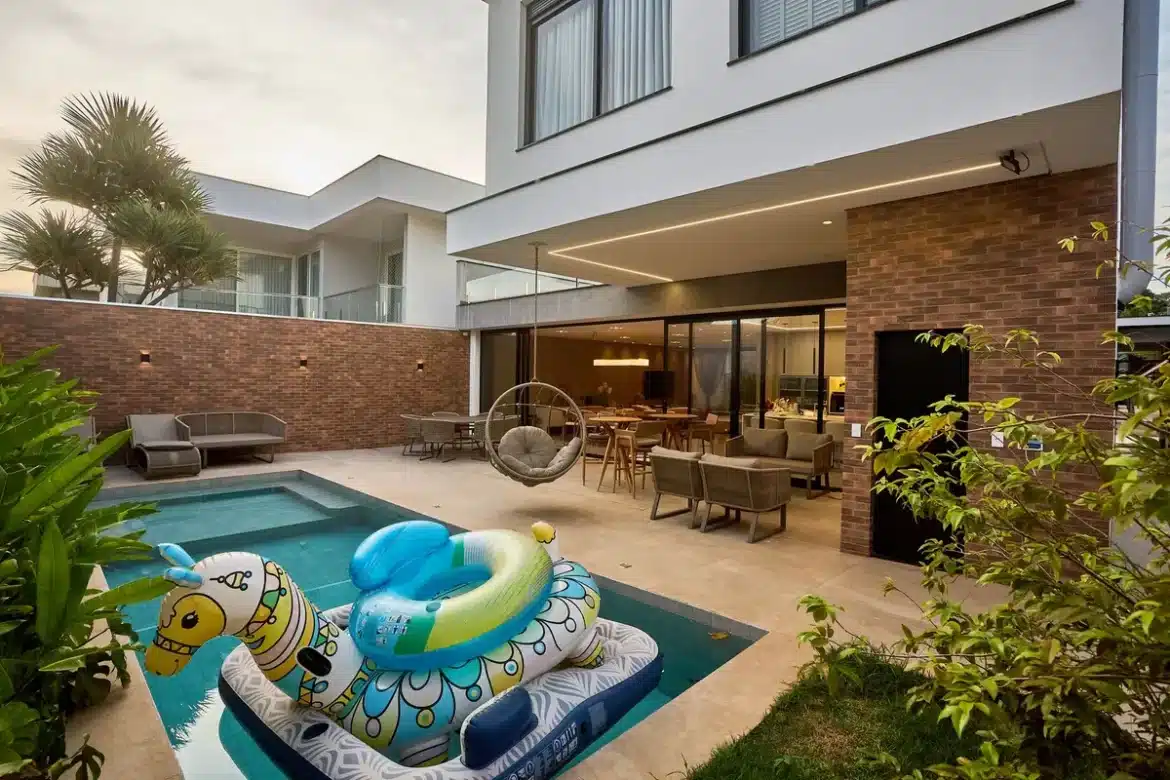 Une piscine rectangulaire ensoleillée entourée de végétation et de transats dans un jardin moderne