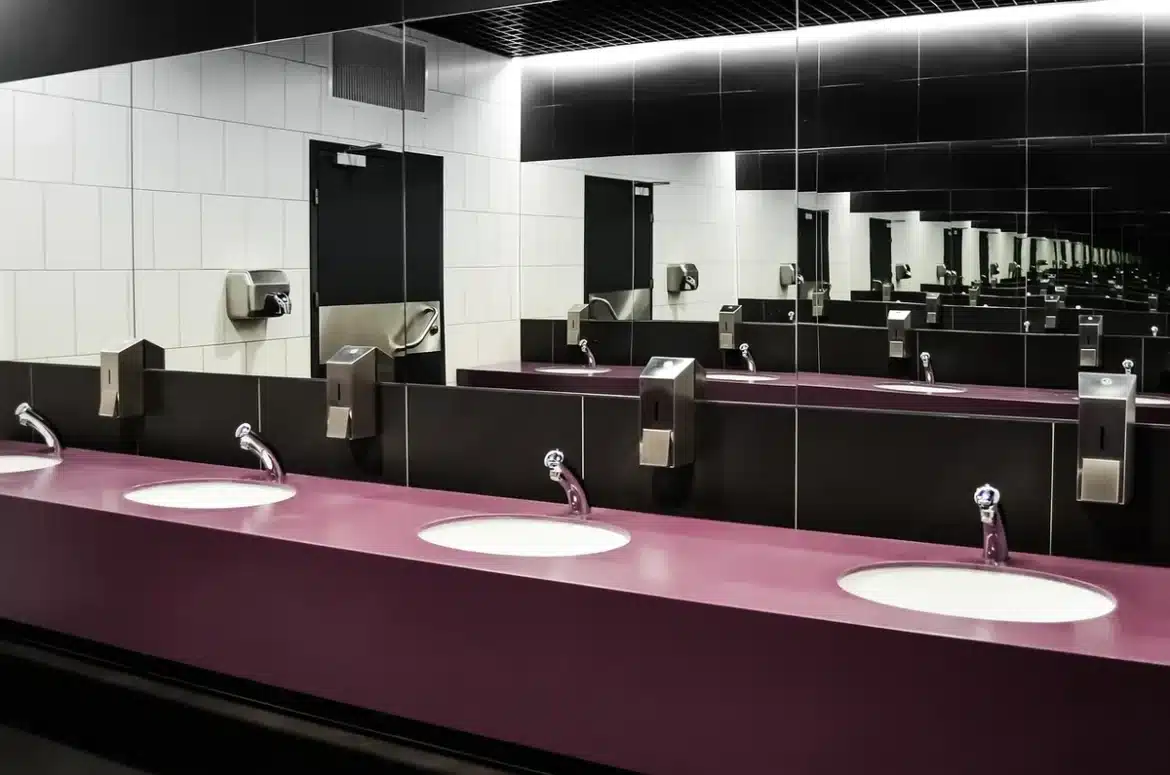 Mains tenant une cuvette de toilettes avec outils de plomberie sur le sol de la salle de bains