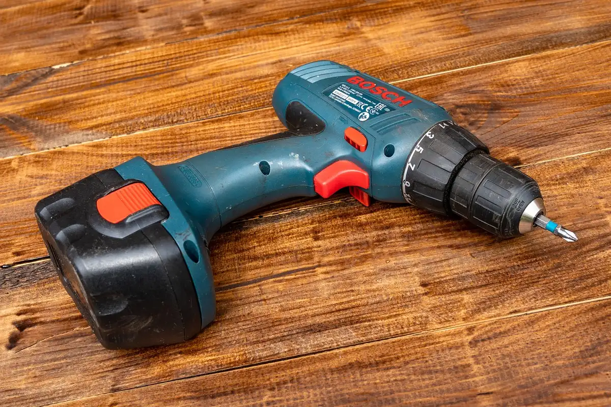 Mains installant une applique extérieure sur un mur avec perceuse et chevilles