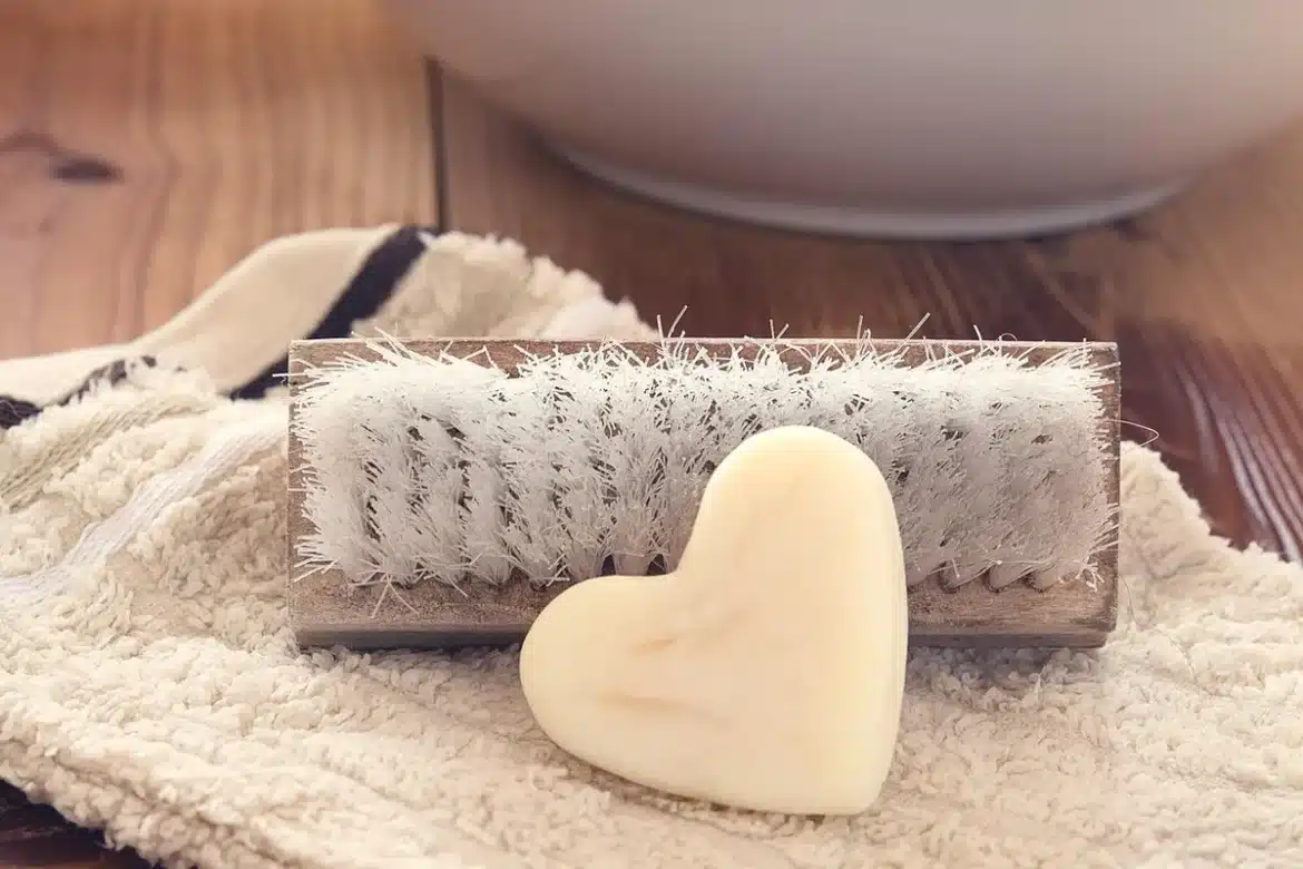 Gros plan sur une dalle en béton claire avec mains gantées et brosse pour nettoyage