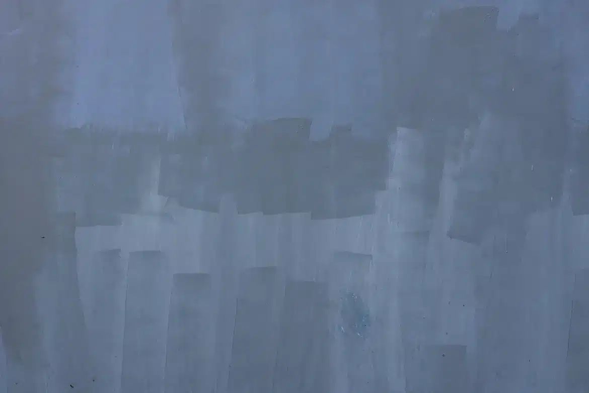 Main anonyme tenant un nuancier devant un mur texturé et une lampe douce