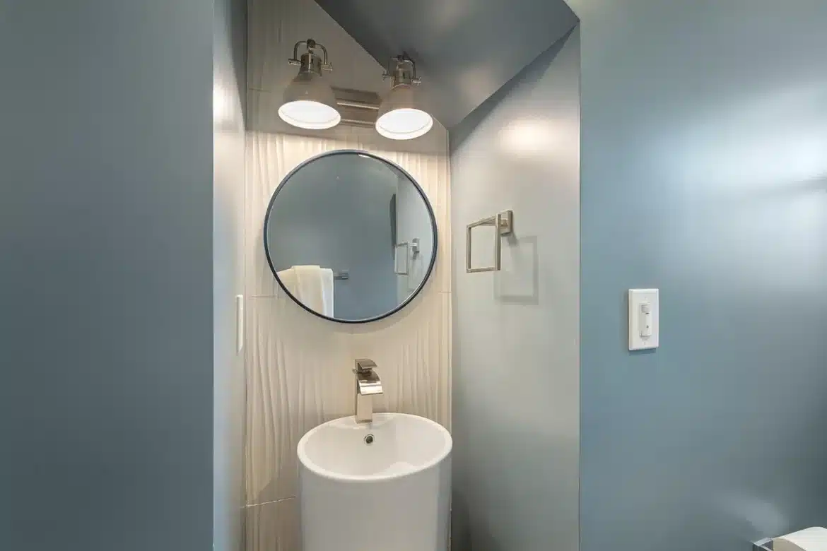 Toilettes lumineuses en journée avec lés de papier peint et outils de pose sur une table