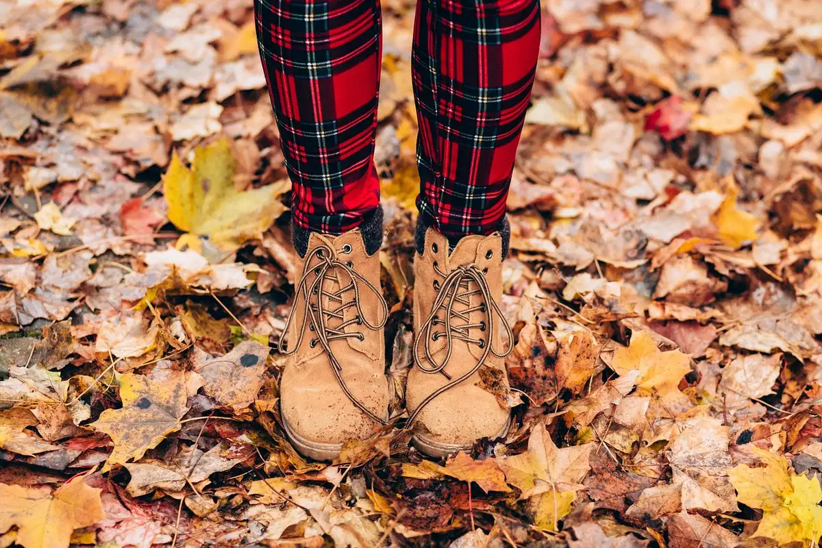 Personne anonyme rassemblant des feuilles sèches sur une pelouse en septembre
