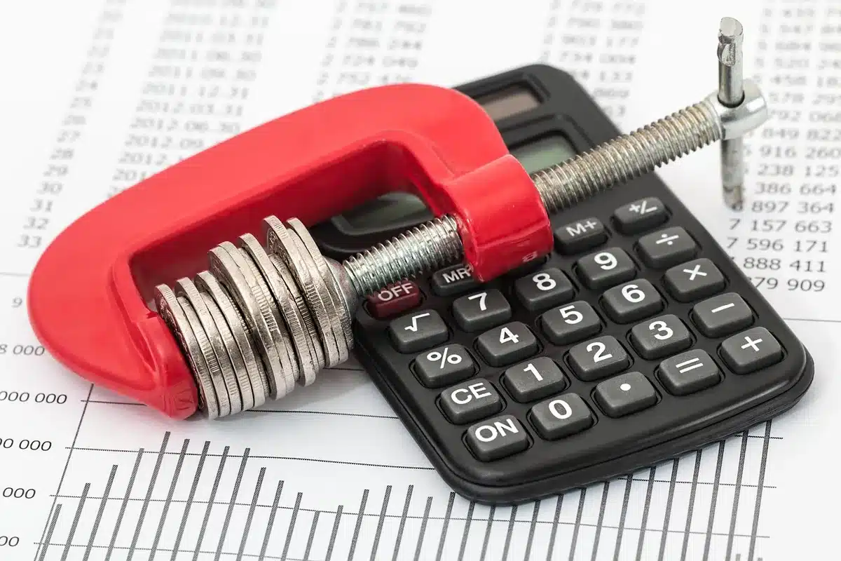 Personne évaluant un budget avec documents et calculatrice sur une table